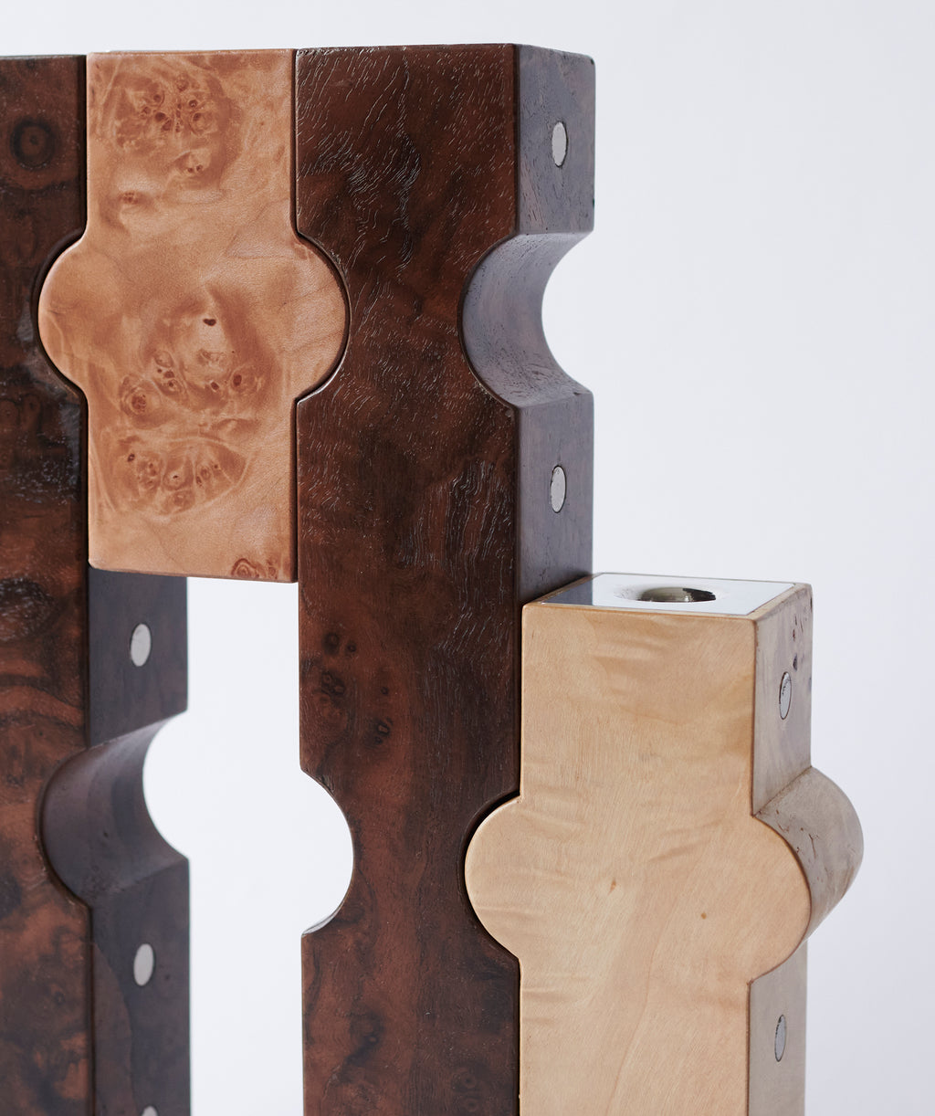 Close up of dark and light wooden candle holders with metal details