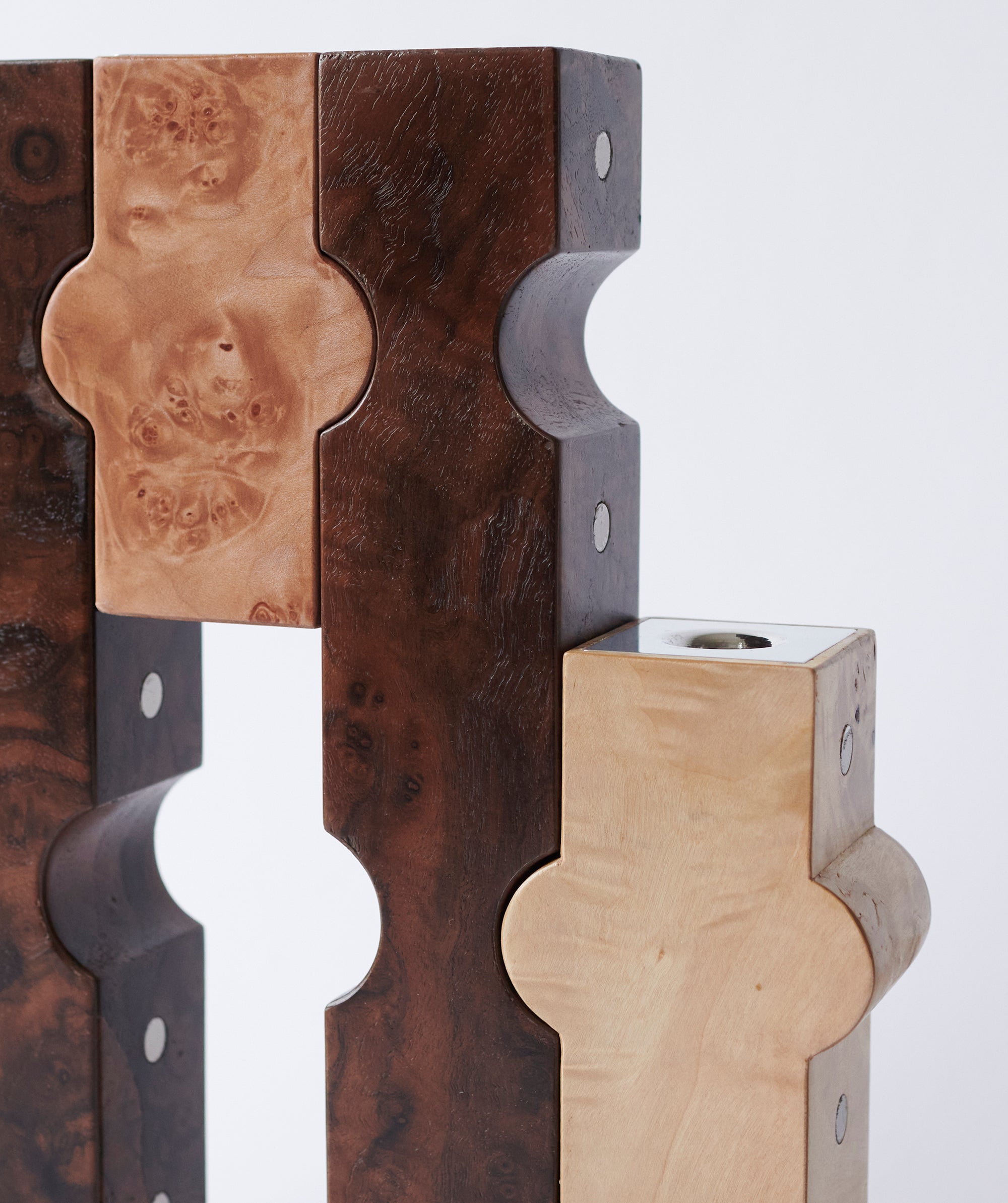 Close up of dark and light wooden candle holders with metal details