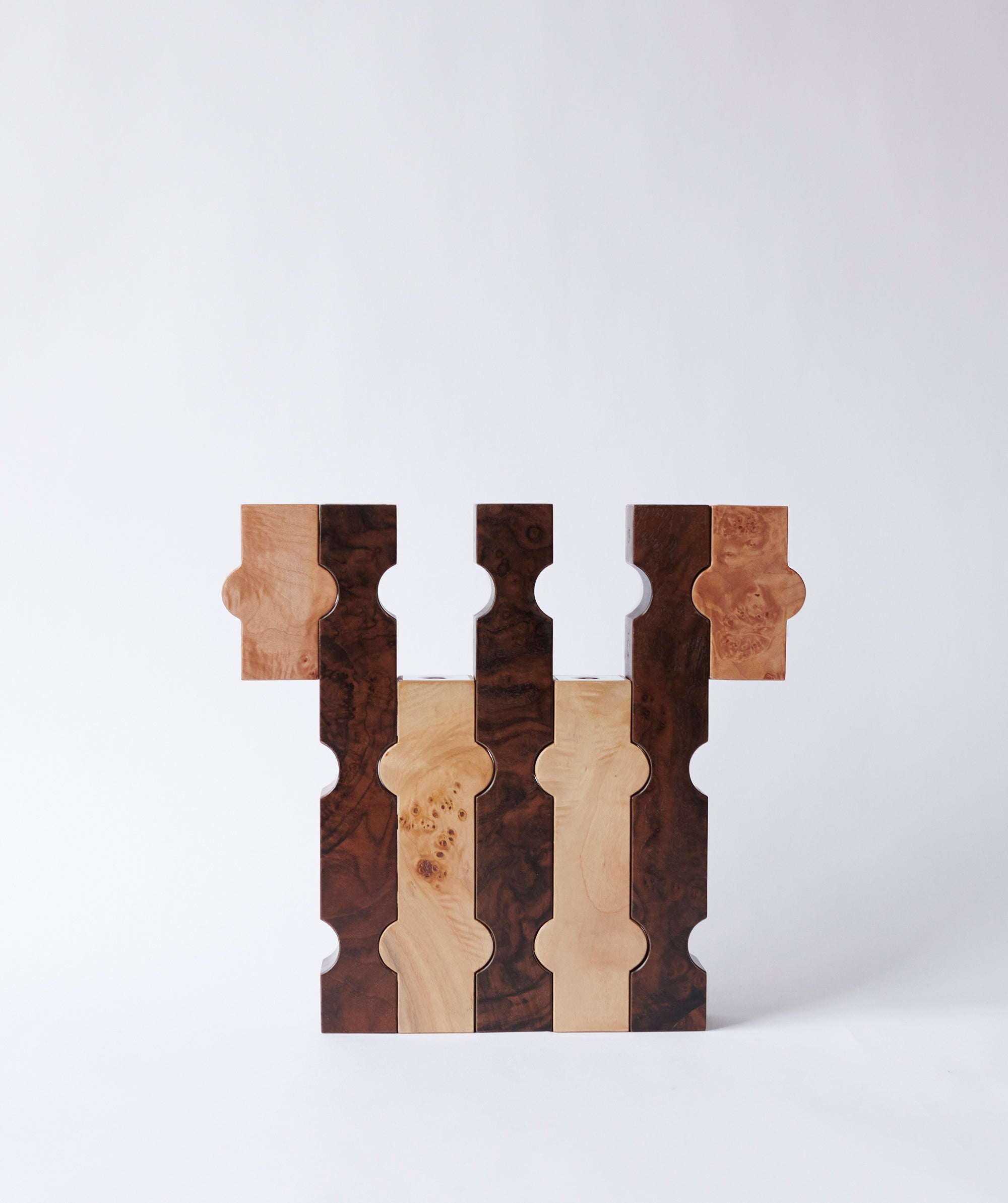 Interlocked sculptural wooden candle holders in contrasting dark and light wood