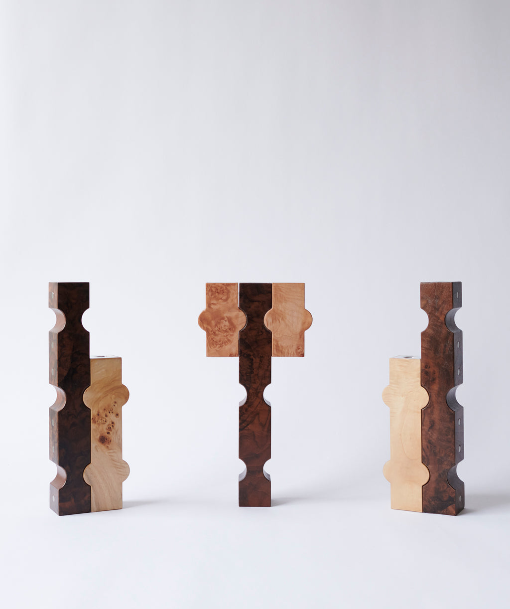A group of sculptural candle holders in dark and light wood