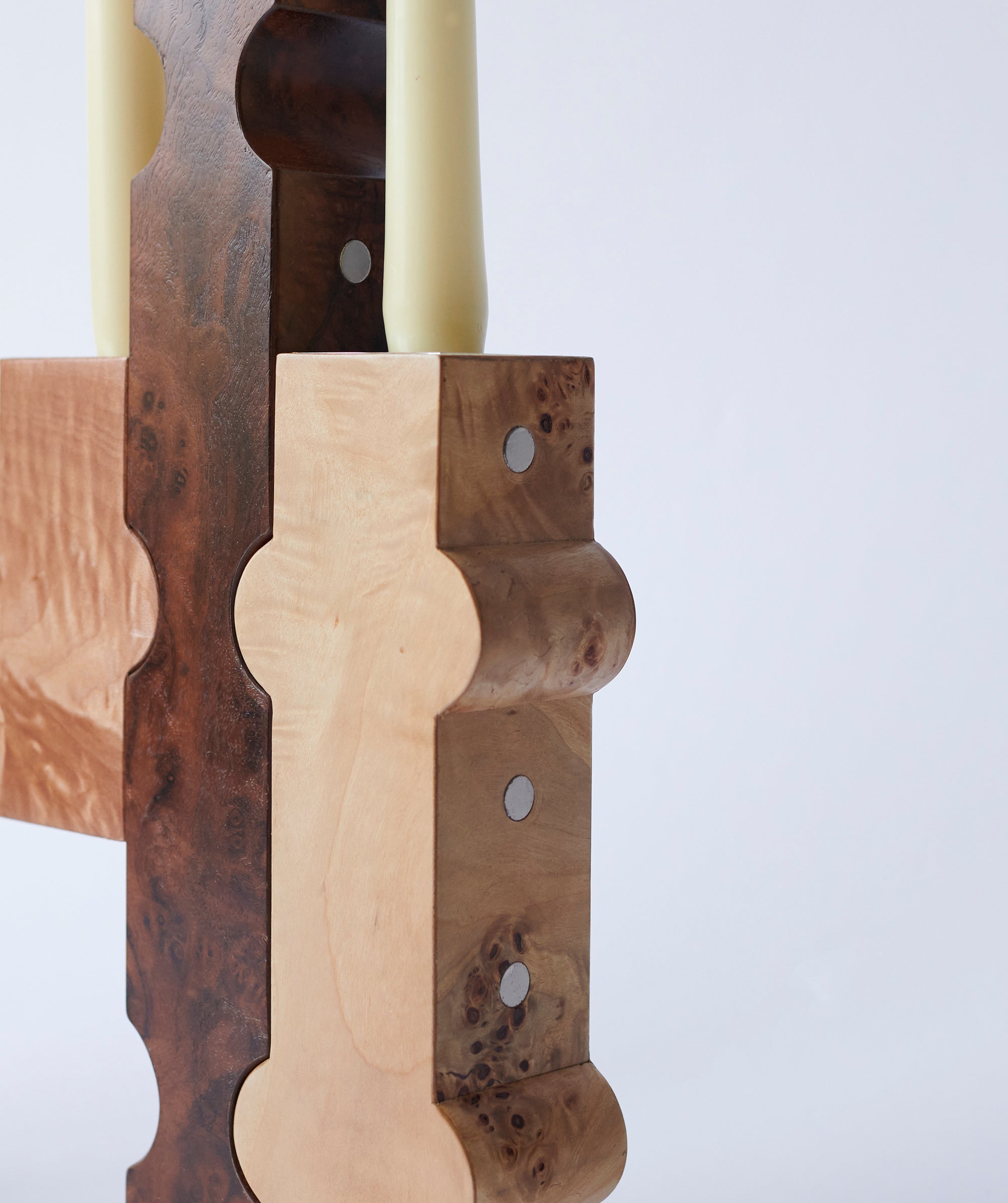 Close up of white taper candle in a polished wood sculptural candle holder