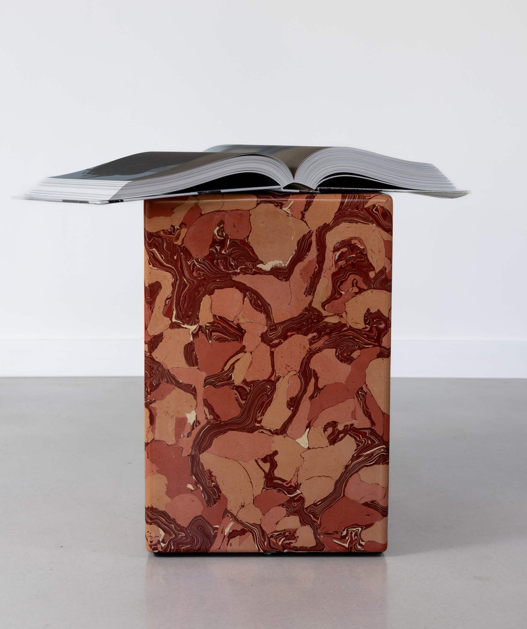 Scagliola marble patterned block sculpture with coffee table book resting on top
