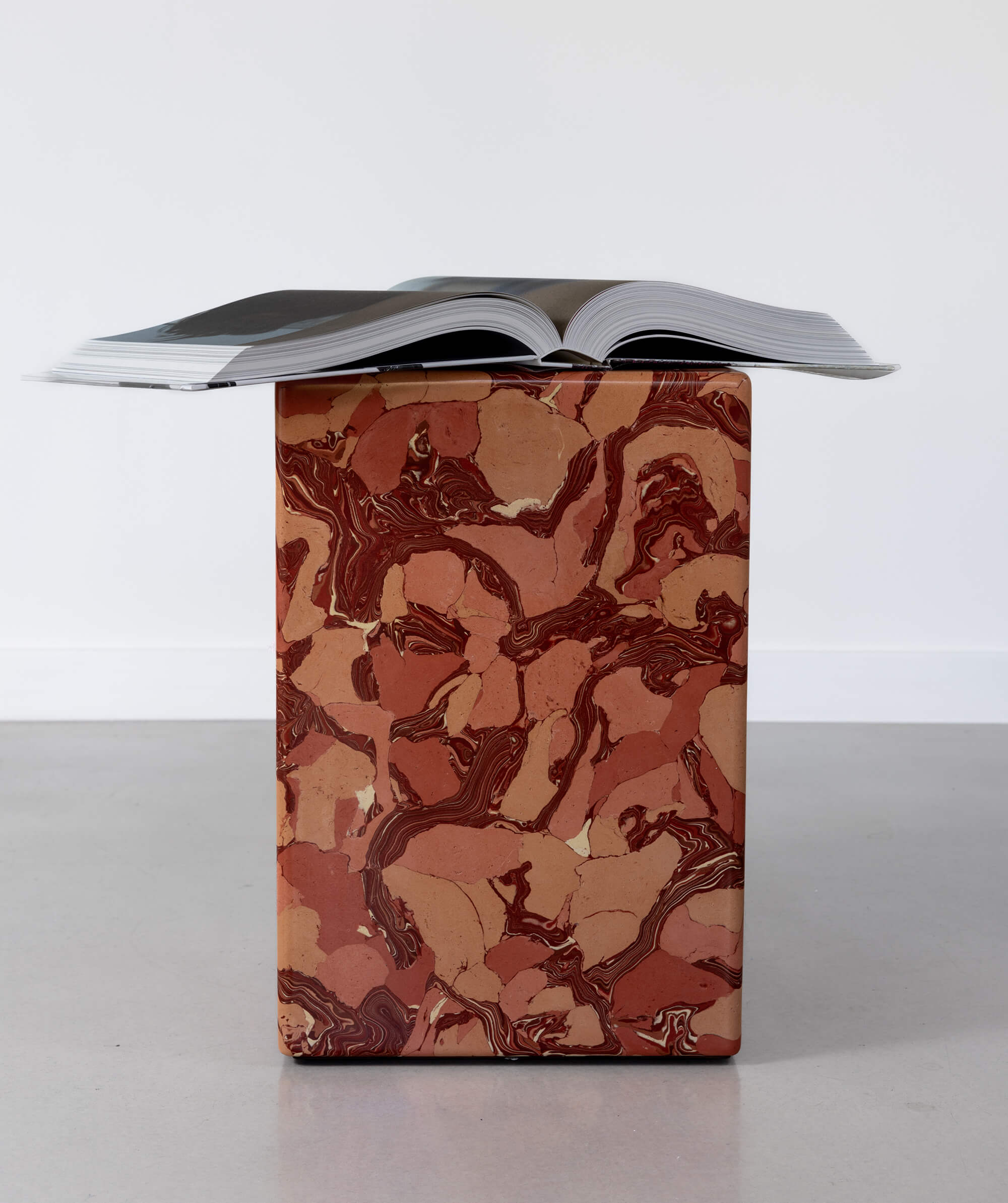 Scagliola marble patterned block sculpture with coffee table book resting on top