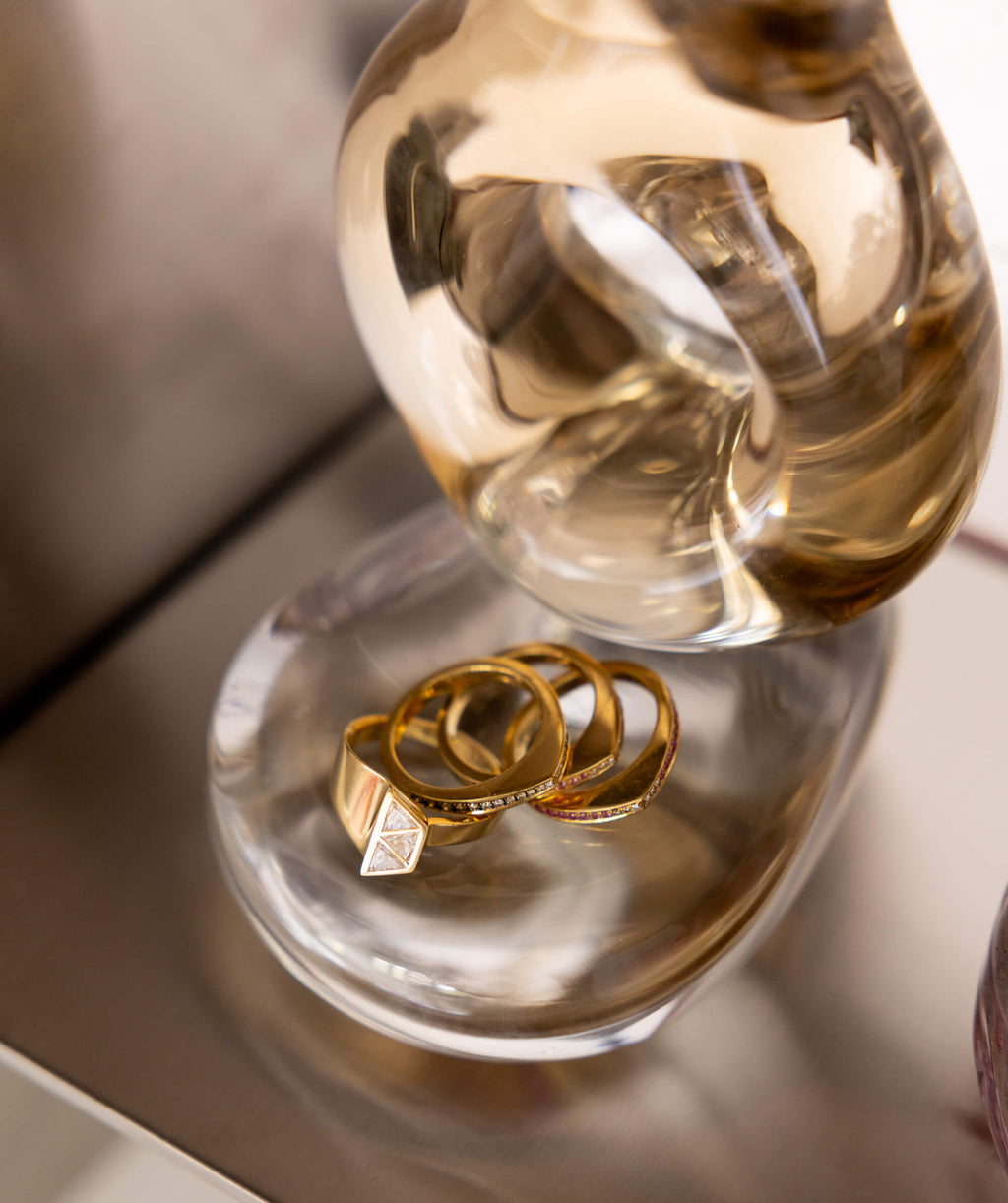 Close up of gold rings with a sculptural glass object