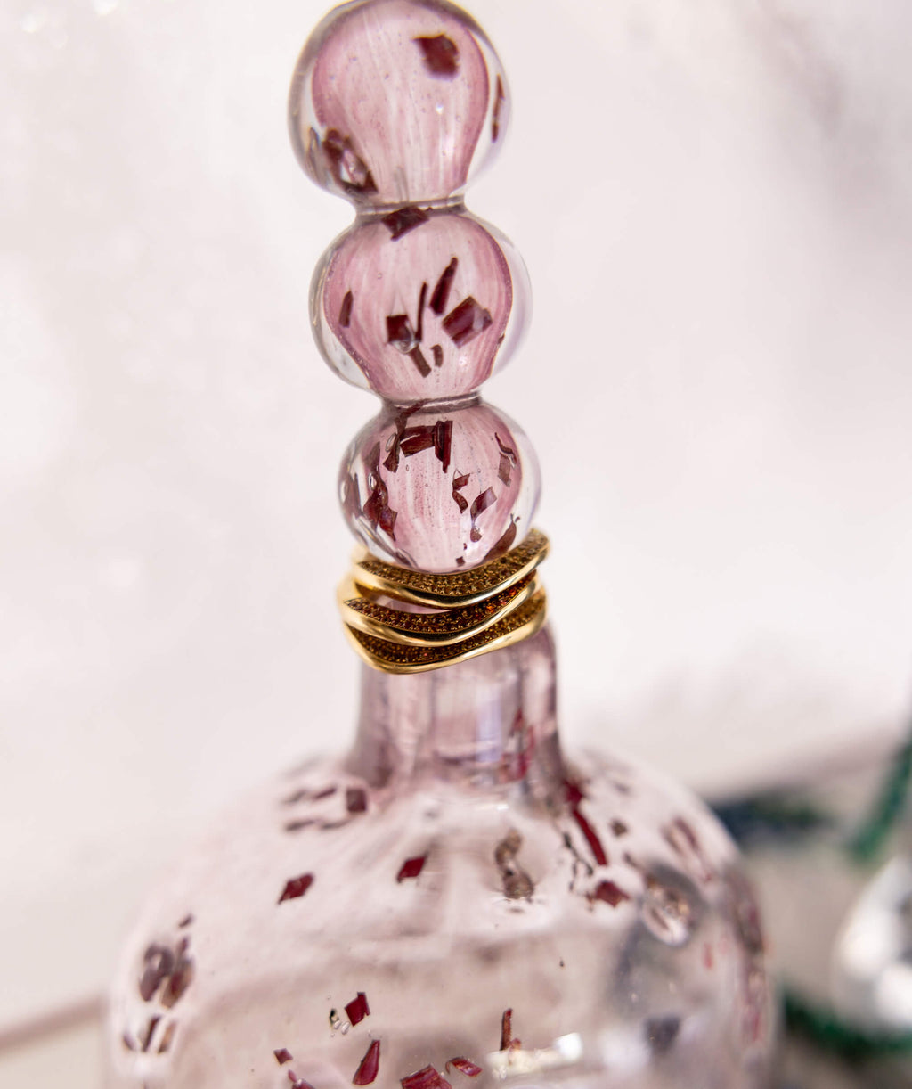 Close up of gold rings stacked on a sculptural pink glass object