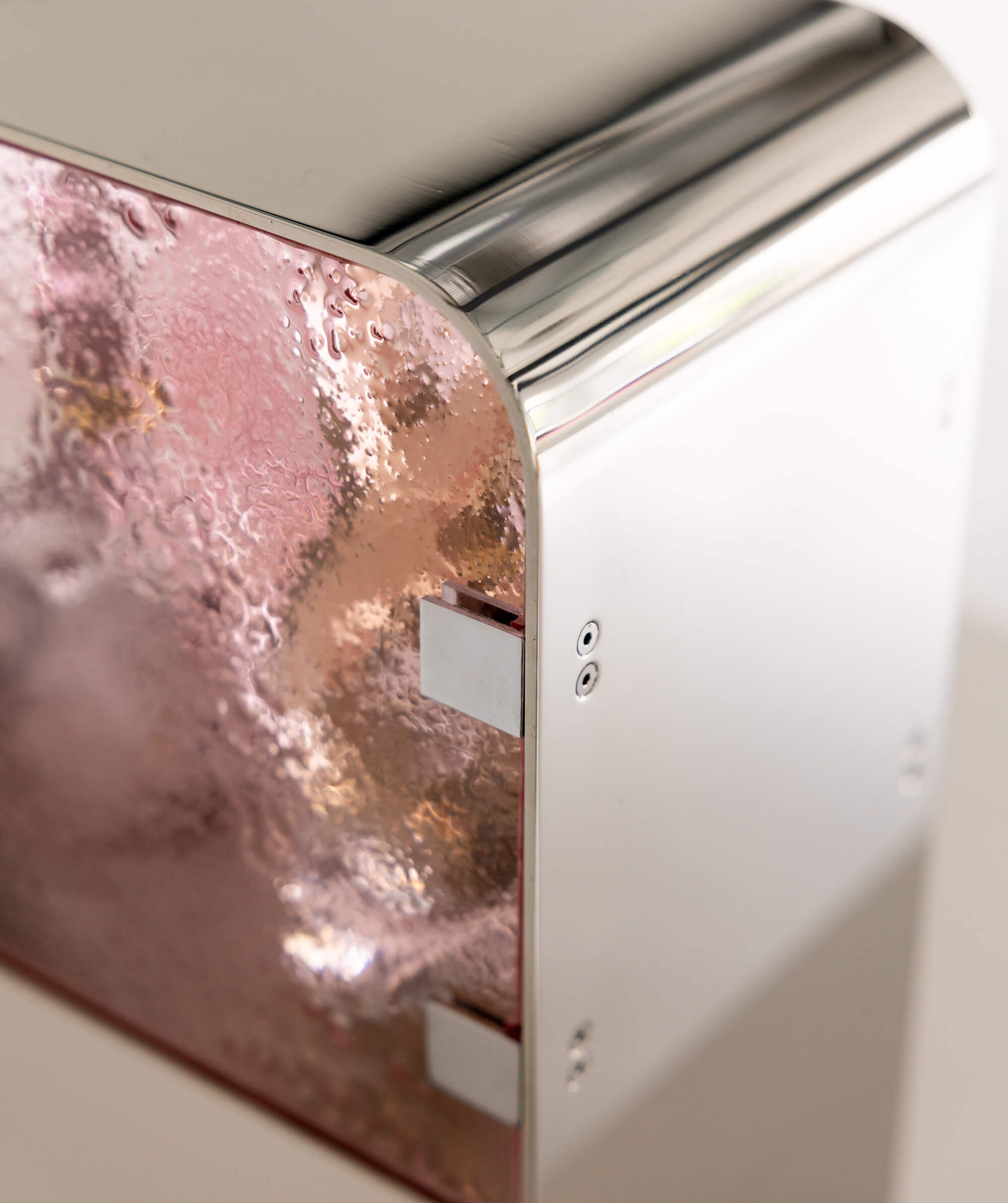 Close up of a curved steel cabinet edge with pink textured glass door