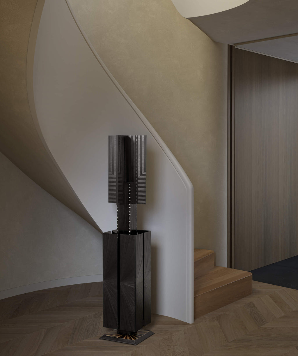 Black, geometric floor standing sculpture placed next to a staircase in a modern room