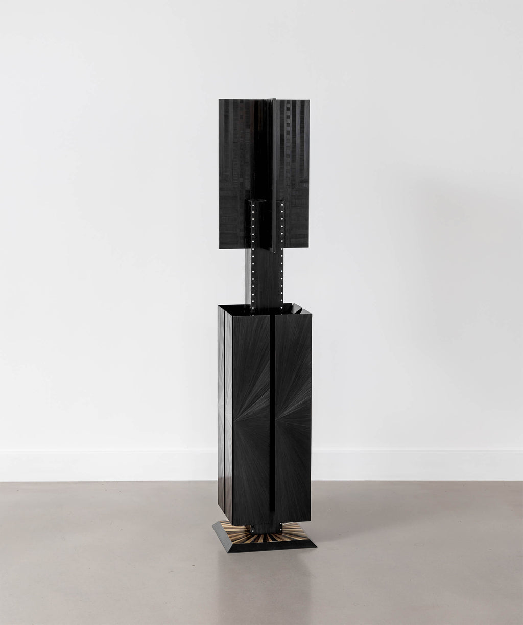 Black sculptural object standing on the floor with a white background