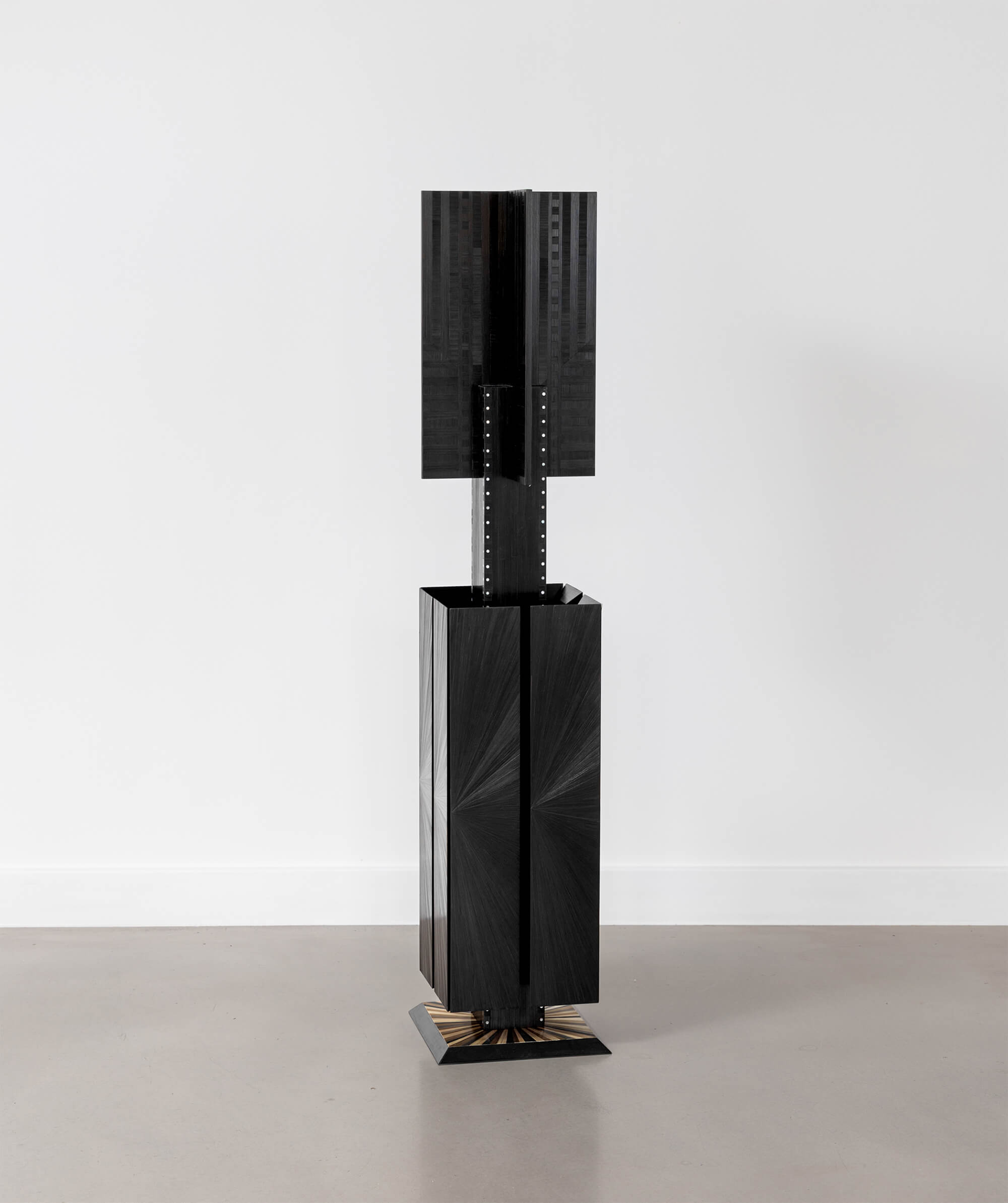Black sculptural object standing on the floor with a white background